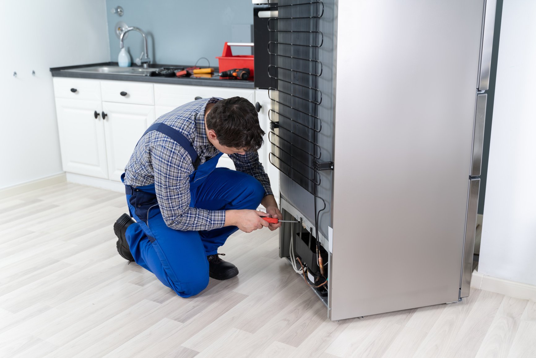 Worker Repairing Refrigerator In House