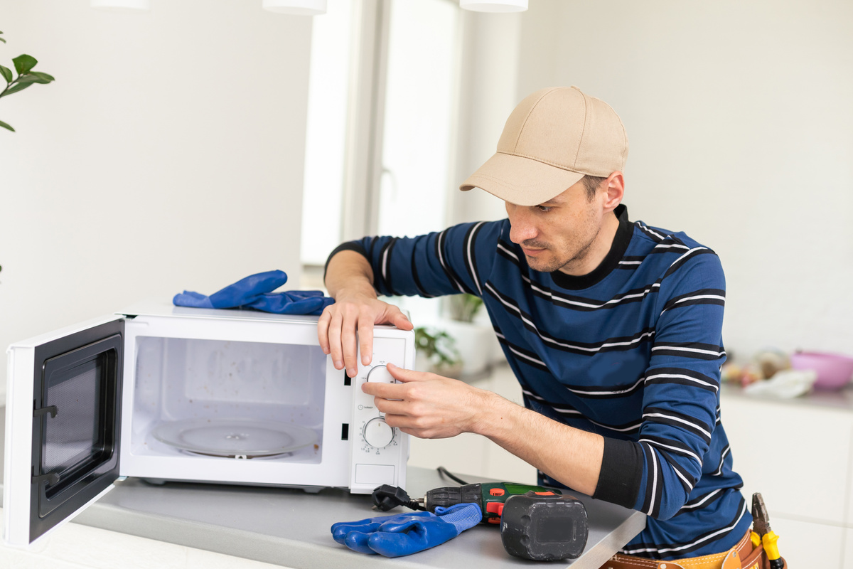 man repairing microwave. a worker repairs a microwave oven.